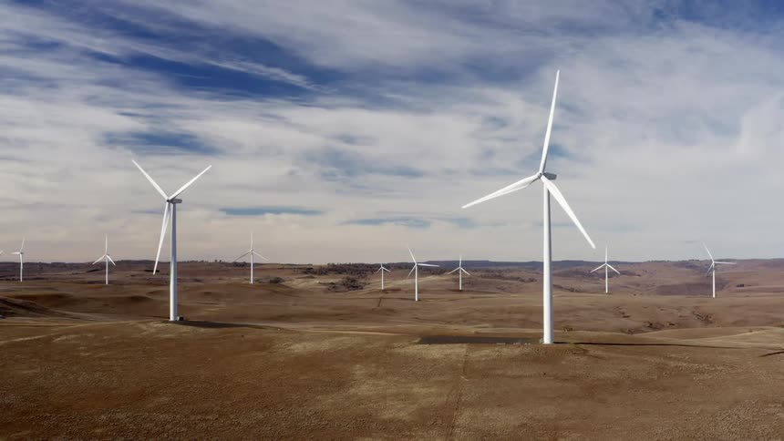 A landscape with a wind turbine farm with the sky and clouds in the background