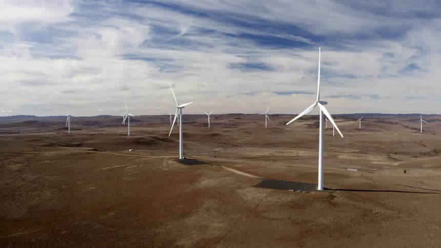 Slowly spinning wind turbines cast shadows under cloudy sky