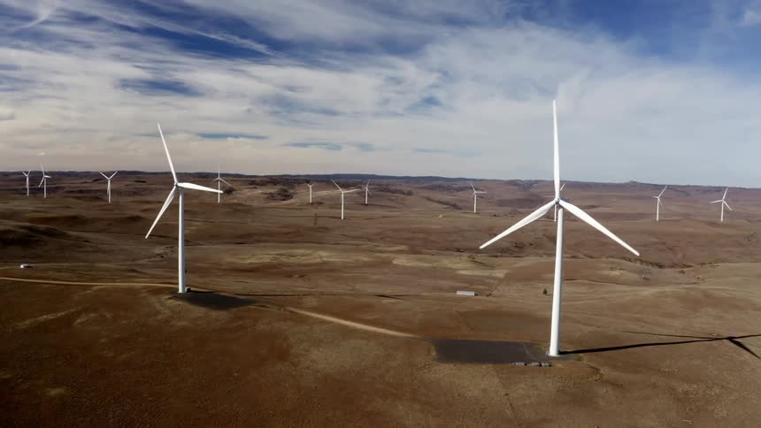 A landscape with wind turbines in a wind turbine farm with the sky and clouds in the background