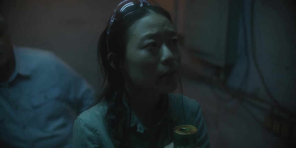 Nervous or fearful woman holding a canned beverage standing inside a dimly lit room
