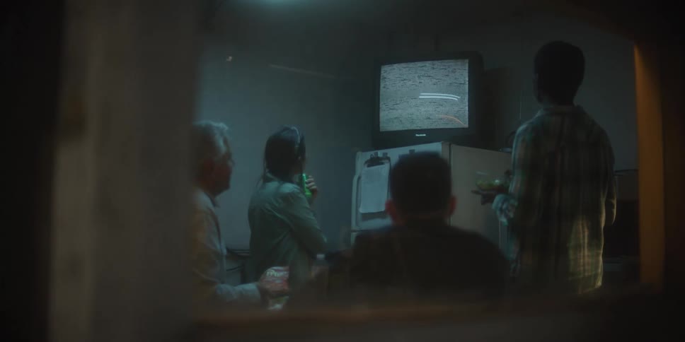 Coworkers gathered around a television displaying static in a work breakroom