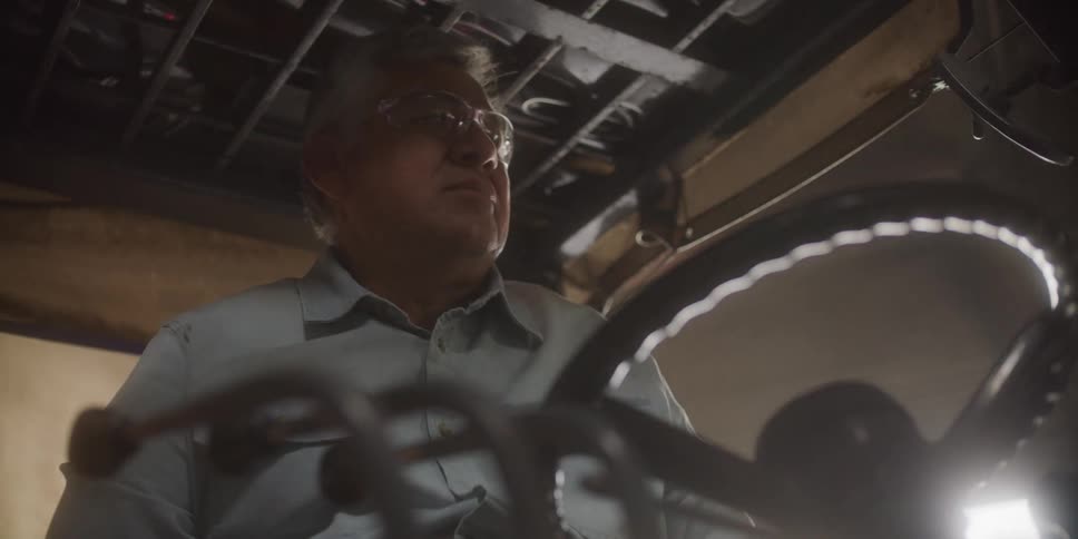 A man in safety glasses driving a forklift in a warehouse
