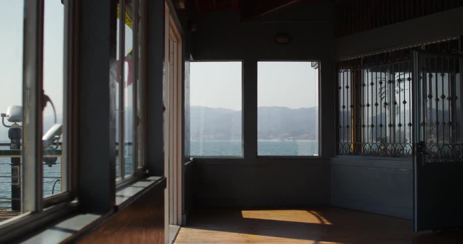 A room with large windows overlooking a body of water on a sunny day