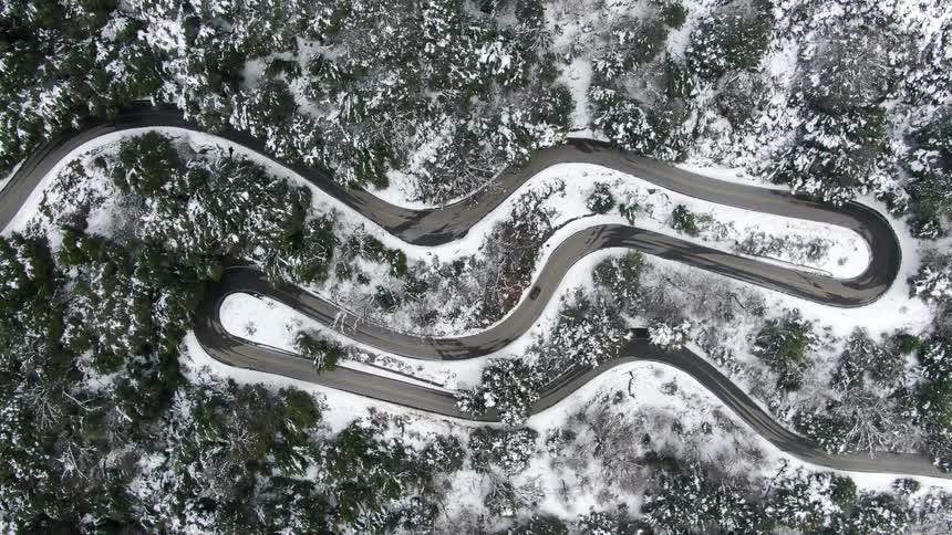 Car traveling on a winding road through a snow covered forest