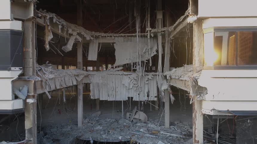 A missing section of a ruined building in a metropolis during the day