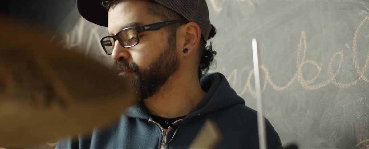A male drummer hitting drum cymbals with a drumstick
