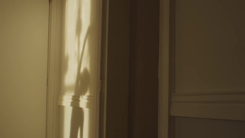 A room with a shadow of a person stretching on the wall next to a doorway