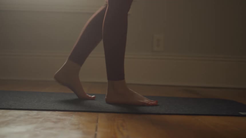A person walking on a mat on the floor with a wall and a window in the background