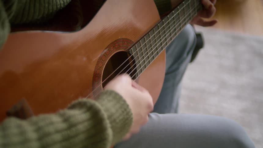 Man sitting outdoors playing acoustic guitar