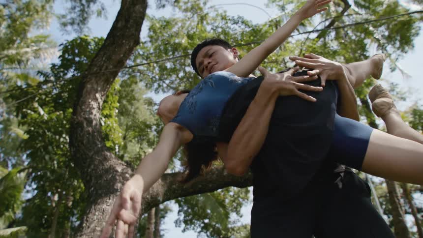A man and a woman dancing with trees the sky and clouds in the background