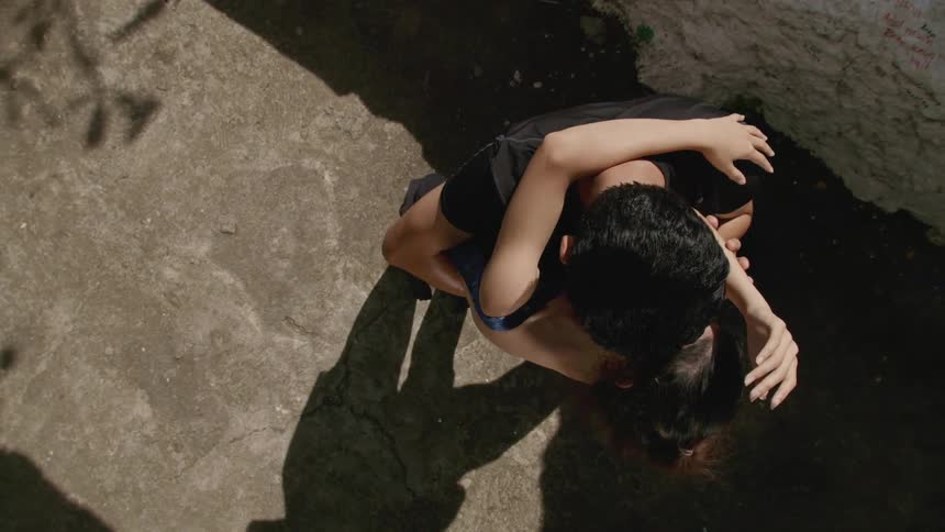 A man and a woman dancing on pavement next to a wall