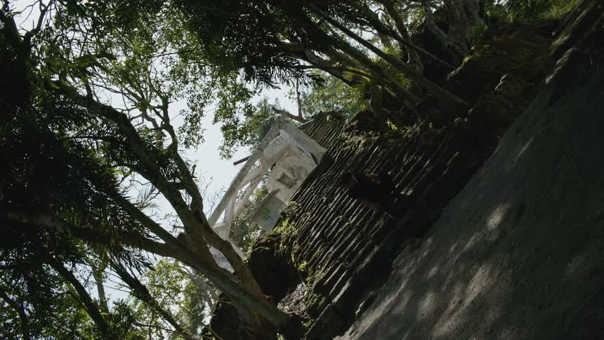 A man dances on a stone outdoor staircase leading to a building on a sunny day