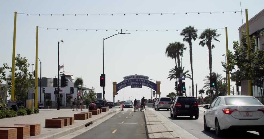 Cars turn left in front of the santa monica pier sign