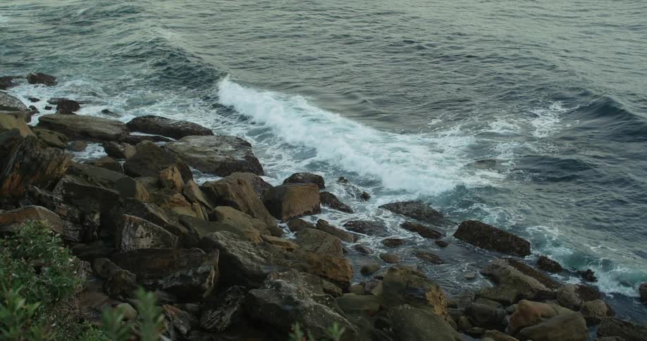 Waves roll toward shore crashing against rocks