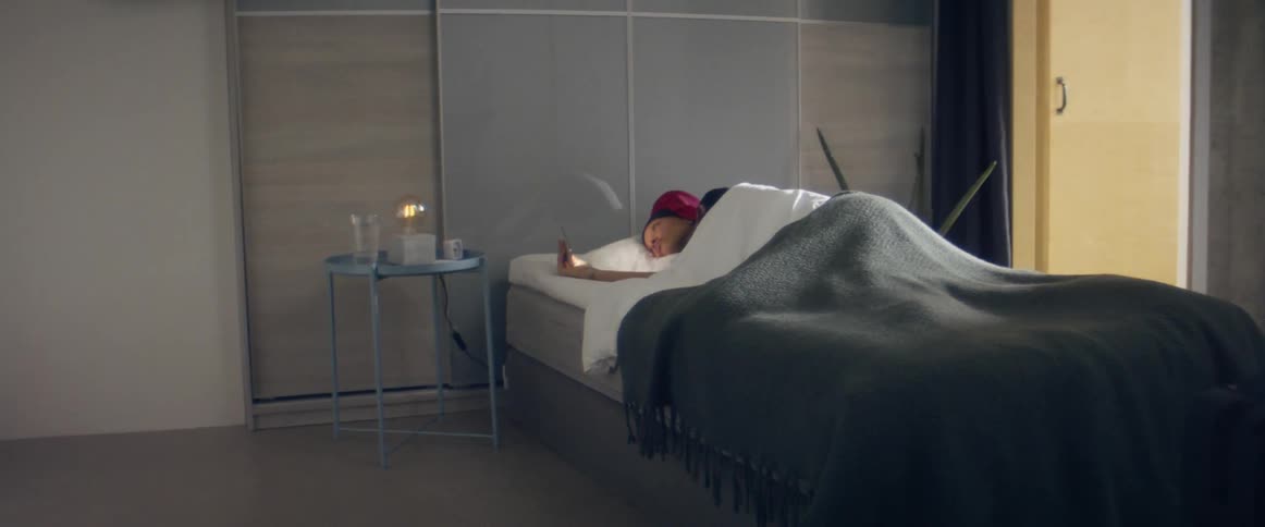 Woman laying in bead looking at her phone in the bedroom at home