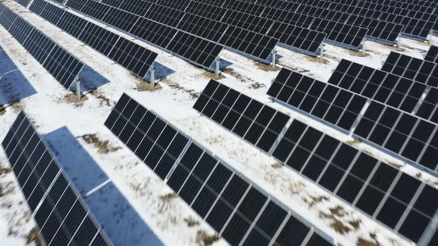 Solar farm with many solar panels and snow on the ground