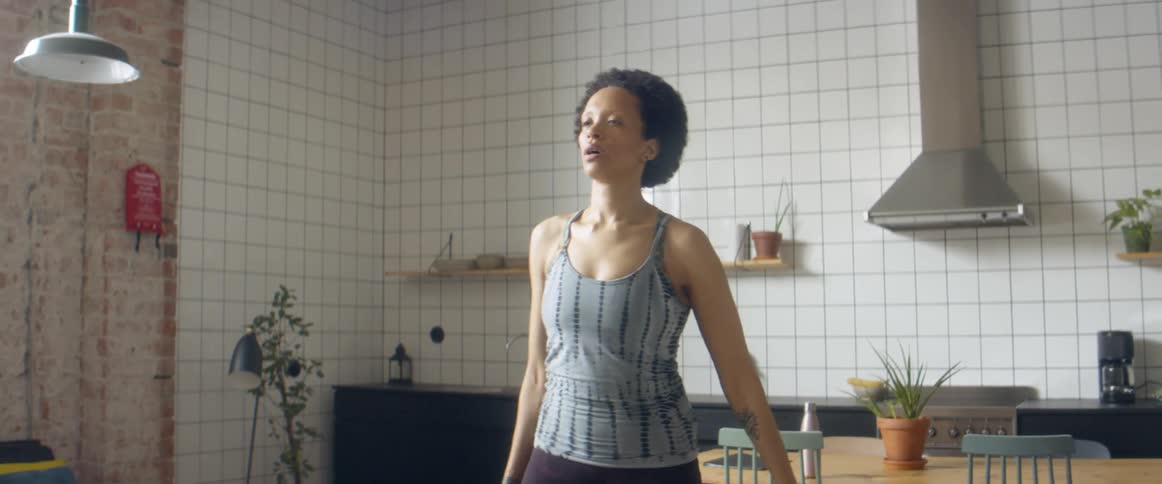 A woman shakes her body before beginning to run in place for exercise indoors during the day