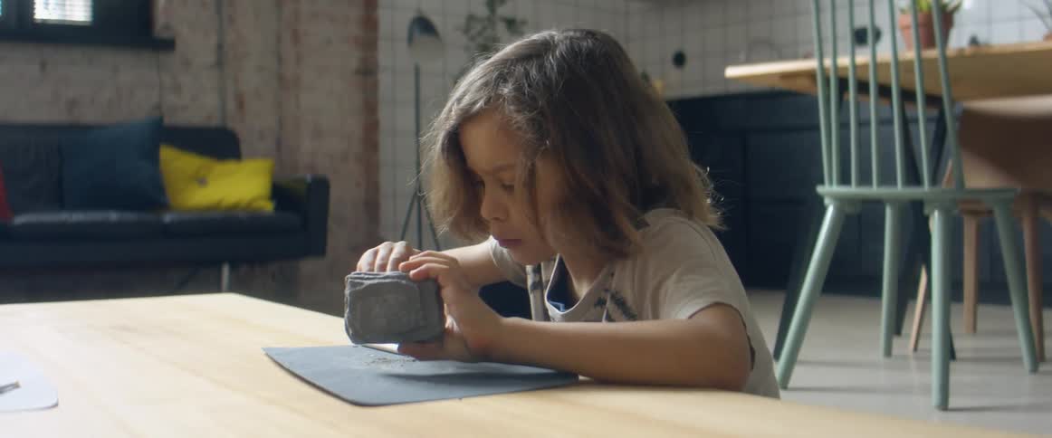A child playing with a rock while sitting in a living room