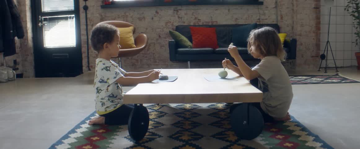 Two brothers playing with clay over the coffee table in the living room