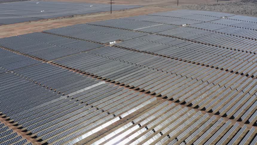 A landscape with a solar farm with utility poles in the background