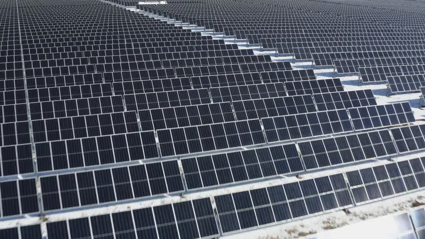 Solar farm with many solar panels and snow on the ground