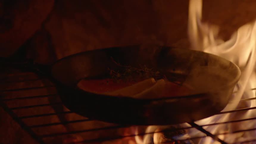 A pan with food sits over open flames