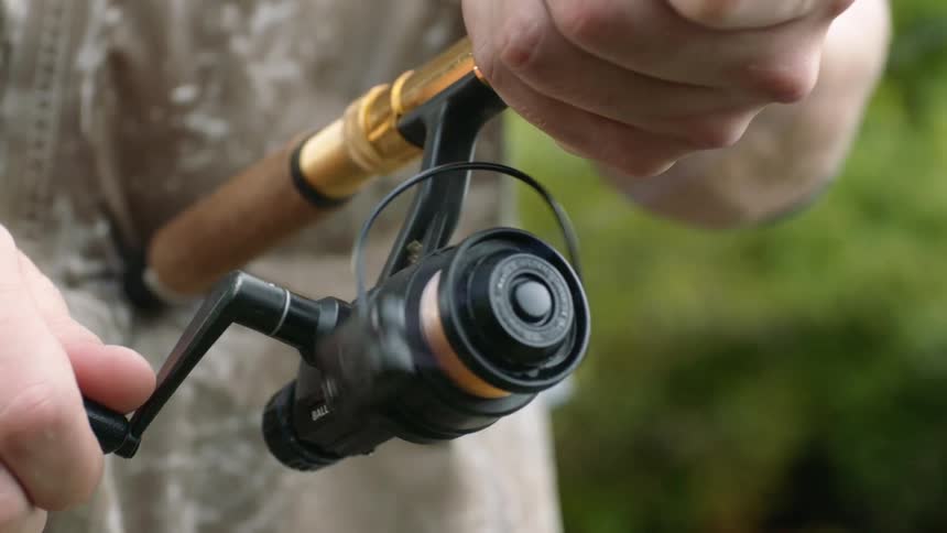 A fisherman holding a pole and reel outdoors