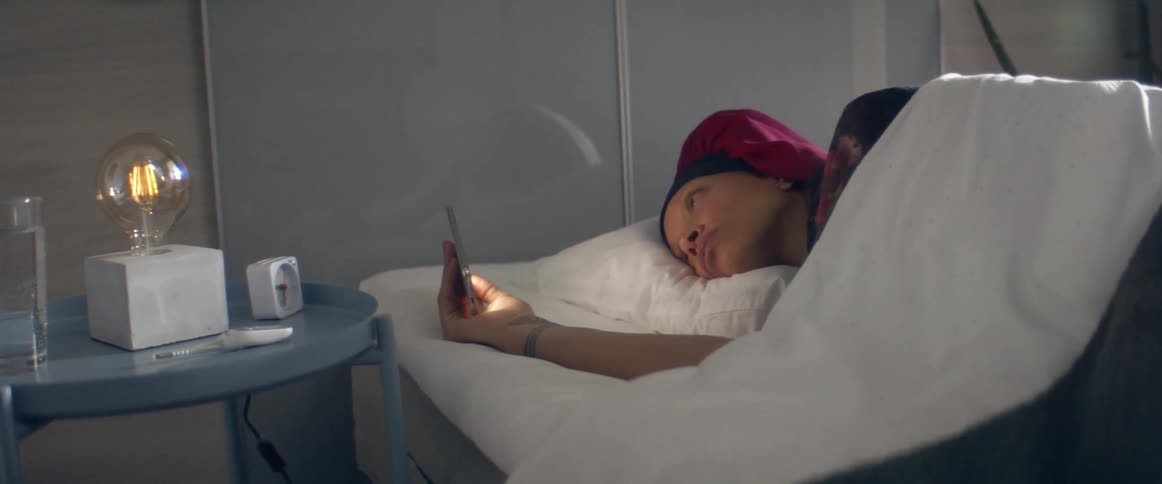 Woman laying in bead looking at her phone in the bedroom at home