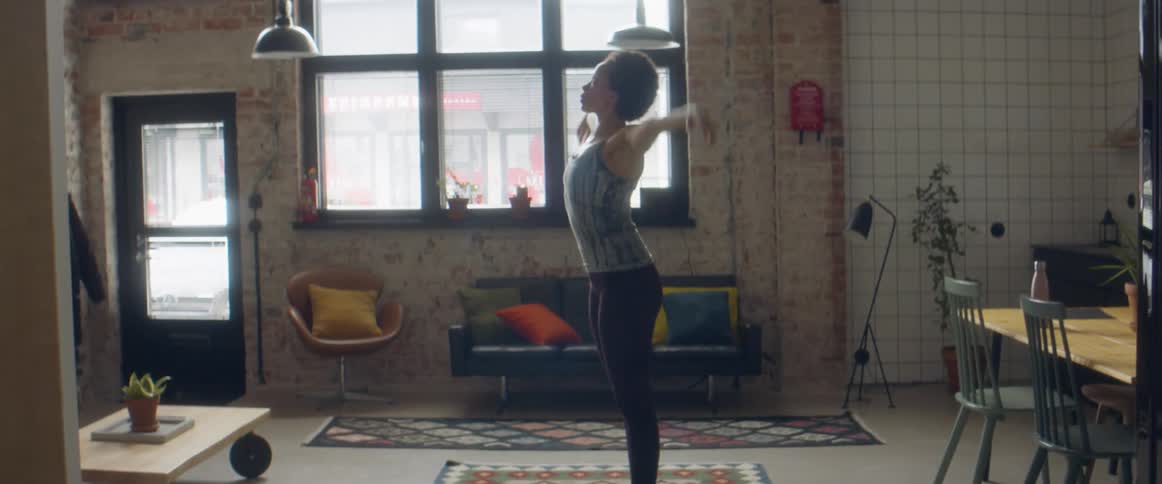 Woman wearing sports clothes working out over a rug in the living room at home