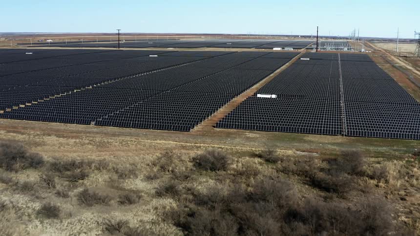 Rows of solar panels on a solar farm located in a field next to a road on a clear day