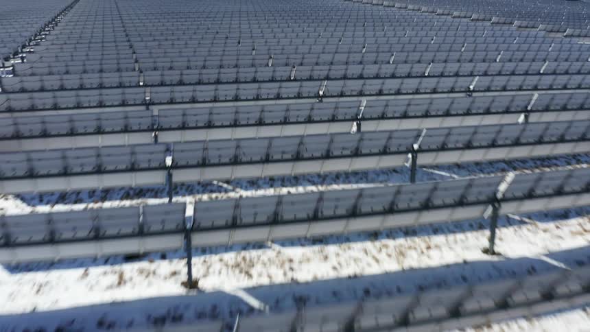 Solar farm with many solar panels and snow on the ground