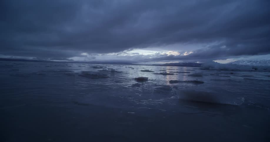 Large chunks of melting ice float in the ocean near an iceberg