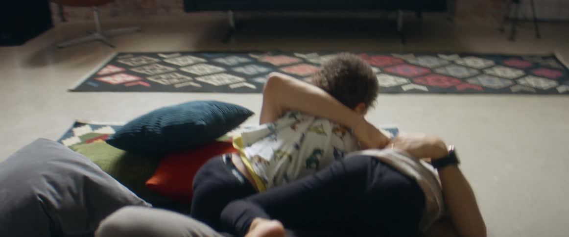 A father is play wrestling with a girl and boy on the living room floor