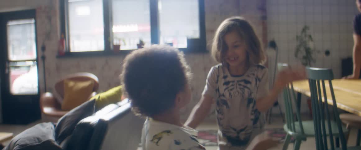 A boy and a girl in a room playing with a wall and a door in the background