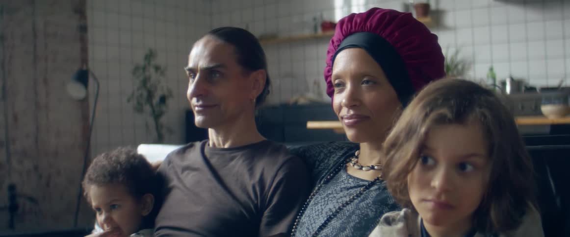 A man and woman sit on a couch with their children