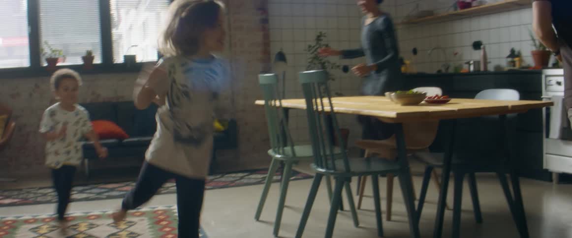 A man a woman a boy and a girl in a room running around a table