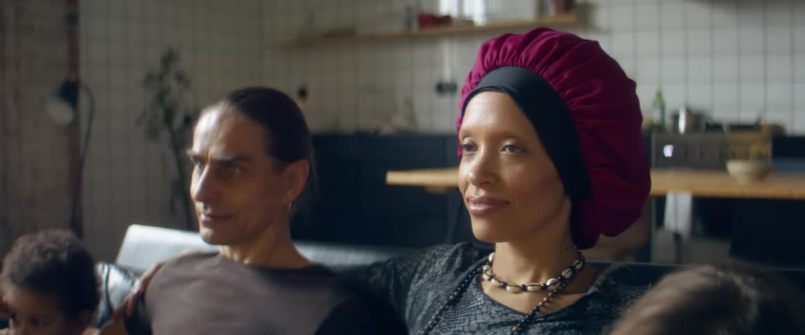 A family sits on the couch together and watches television