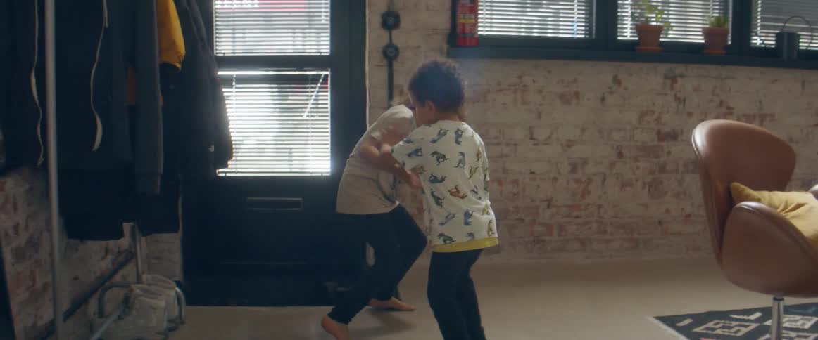 A young boy and girl play fight in their living room