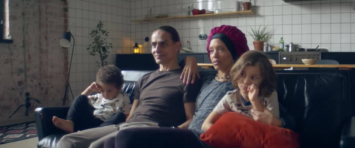 A family watching television on a living room sofa