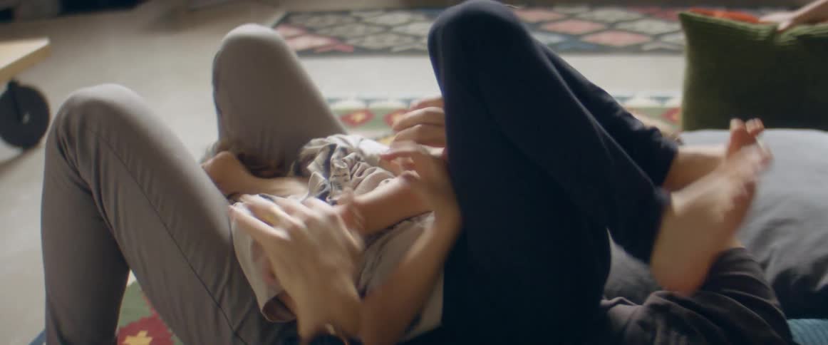 A grandparent tickling their grandchild while lying on a living room rug