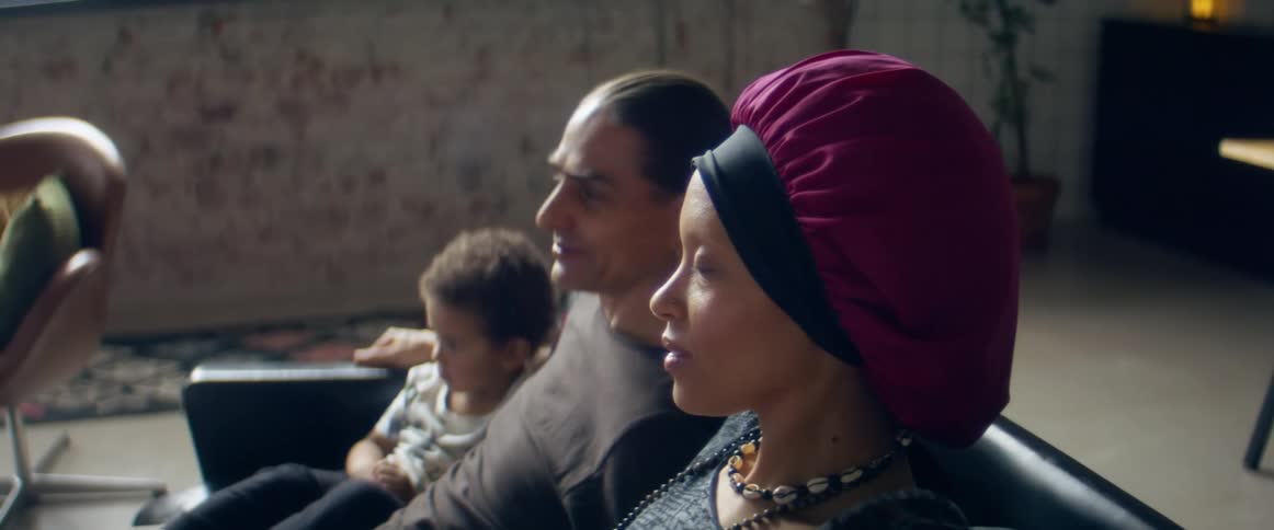A couple and their son sit on a couch close together