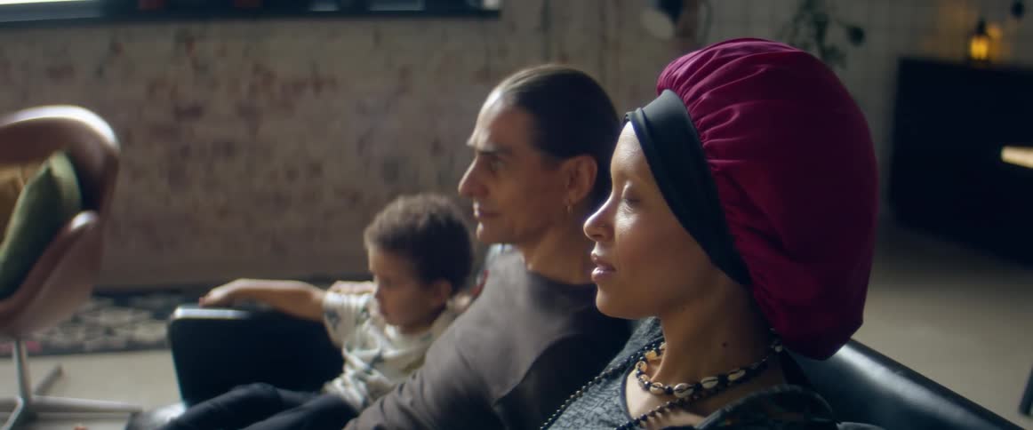A woman speaks while sitting on a couch with a man and a small child
