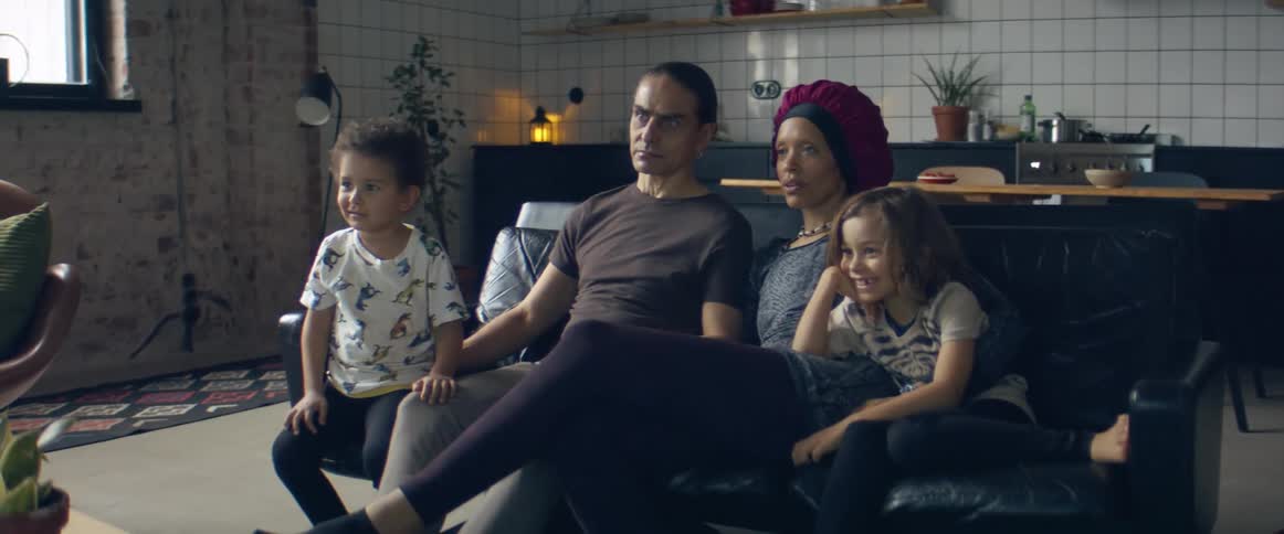 A man a woman and their boys in a room sitting on a couch