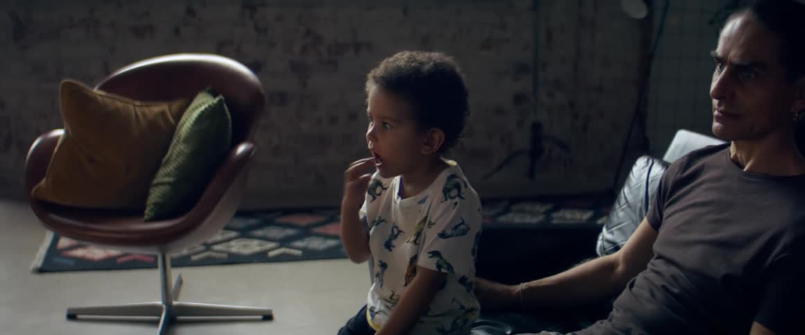 Father and son watching television in the living room at home
