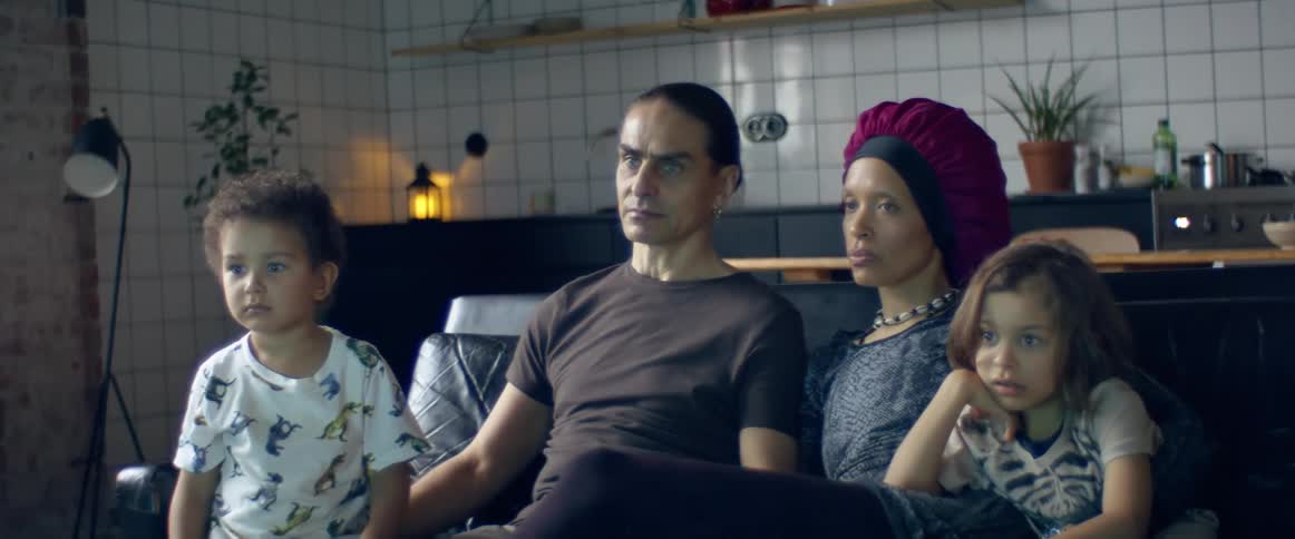 A man and woman sit on a couch with their two boys
