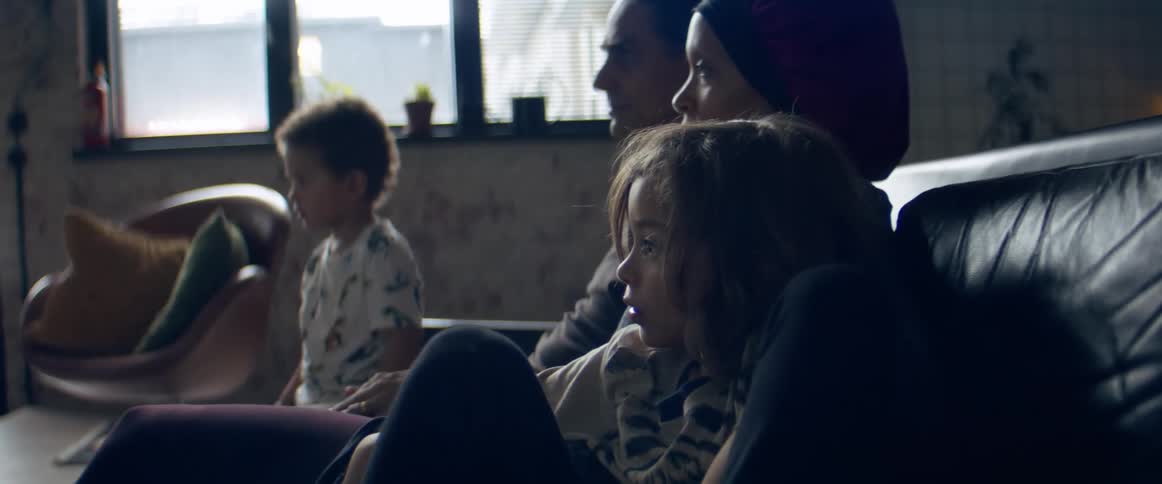 A family sitting on a couch watching television