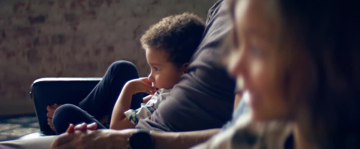 A man a woman and two boys in a room sitting on a couch
