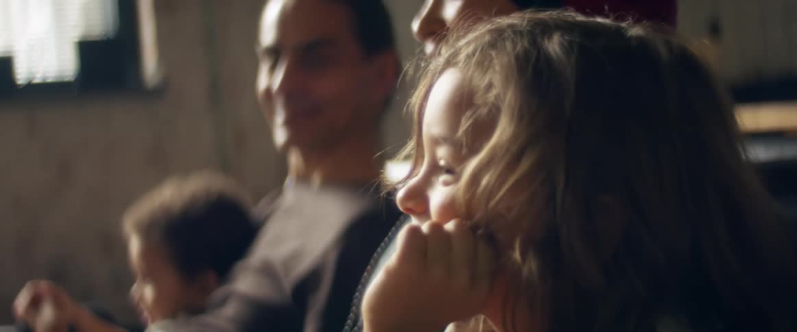 A man a woman and two boys in a room sitting on a couch