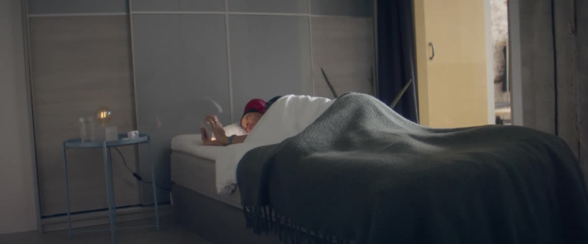 A woman lays in bed looking at her phone