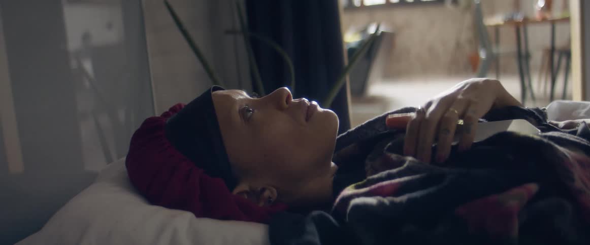 Woman laying in bed looking at her phone in the bedroom at home
